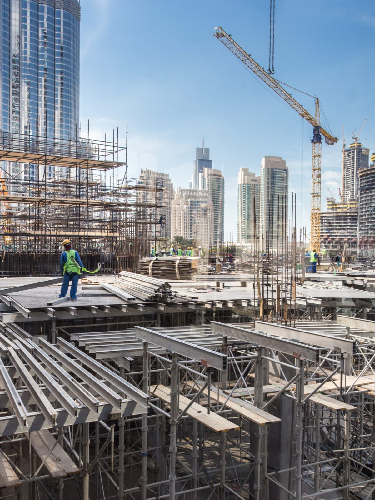 Laborers working on modern constraction site works in Dubai. Fast urban development consept.